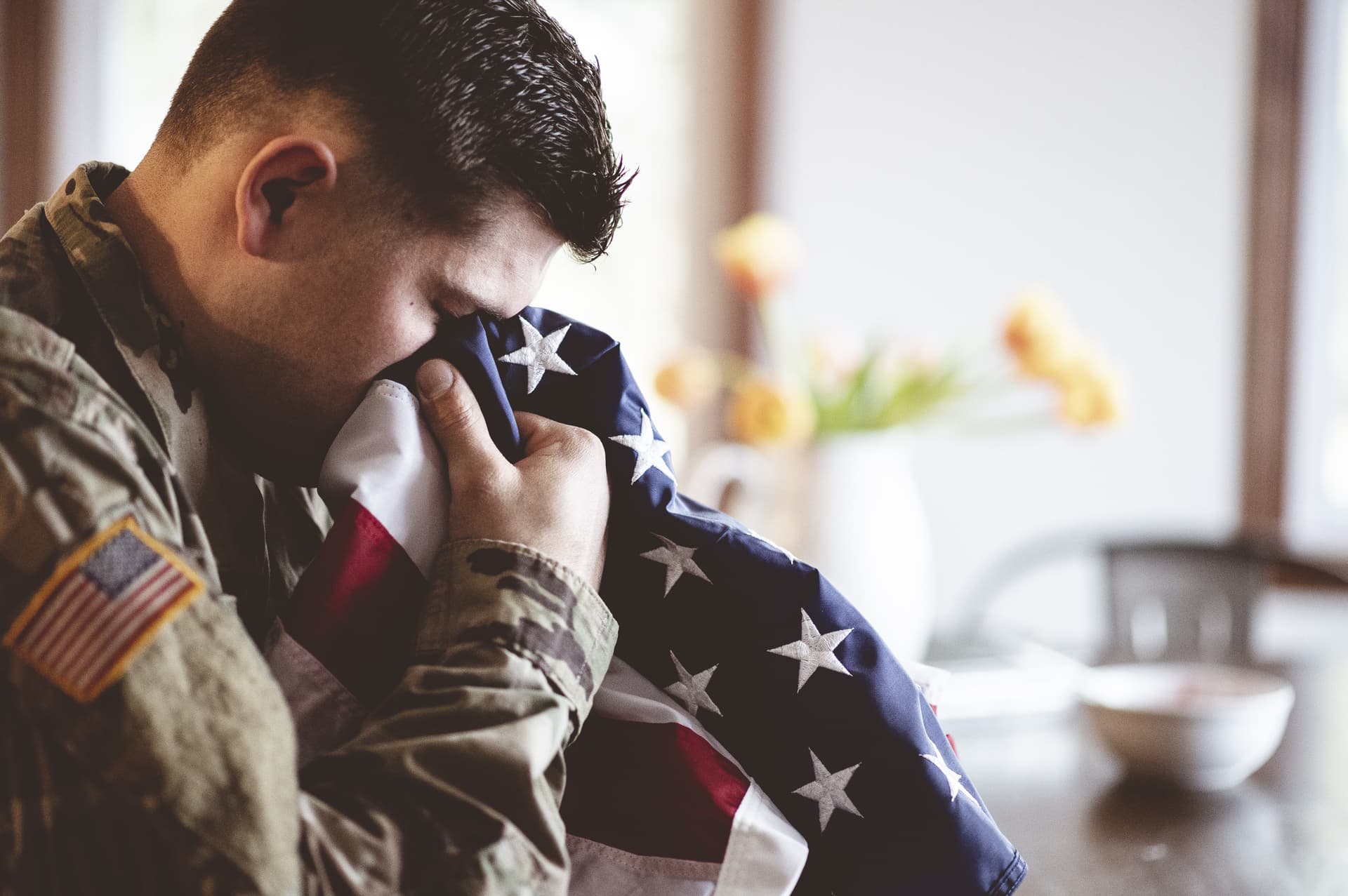 Stock photo: a veteran with head bowed and an American flag held in clasped hands